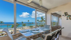 Comedor con vista al océano, amplias ventanas y una mesa dispuesta para cuatro.