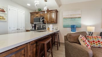 A kitchen with wooden cabinets, a large island, and a bar stool.