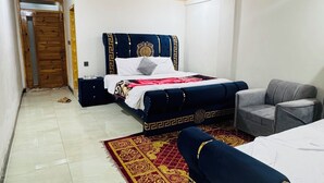 Una habitación de hotel con una cama, un sofá, una mesita y un cubo de basura.
