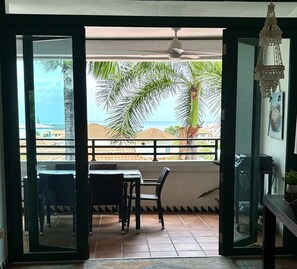 A balcony with a table and chairs, a view of the sea, and a palm tree. - Spacious 3 bedroom Rio Mar Villa with Spectacular Ocean View & Golf Cart! (Río Grande)