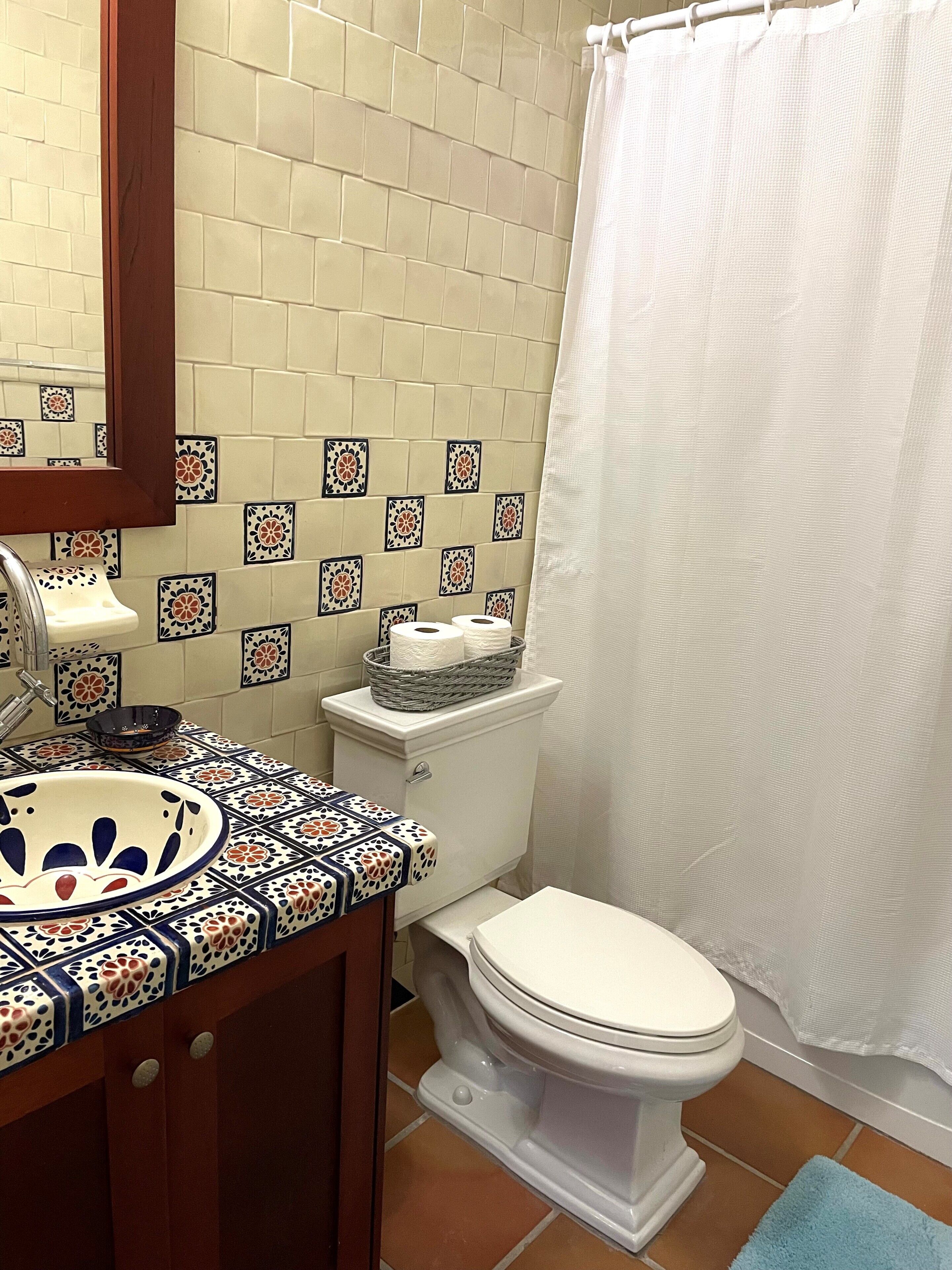A bathroom with a toilet, sink, and shower curtain.