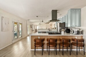 A modern kitchen with a central island, bar stools, and light blue cabinets.