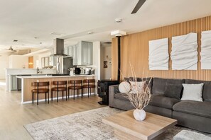 A modern living room with a sofa, coffee table, and a kitchen area with a bar.