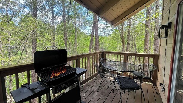 Una veranda coperta con barbecue, sedie in metallo e tavolo.