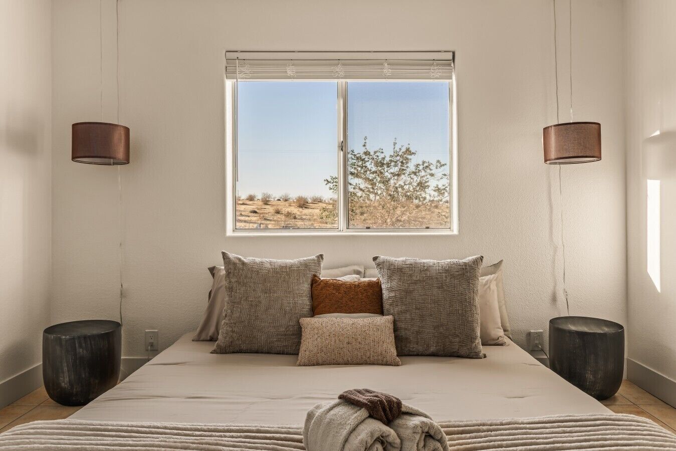 Un dormitorio con una cama grande, dos lámparas de noche, una ventana con vistas y una mesita de noche.