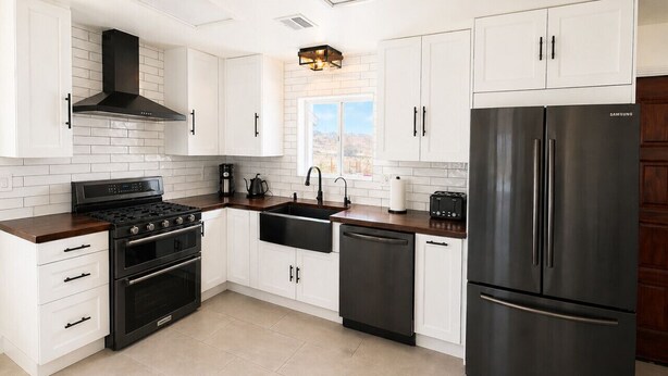 Una cocina moderna con armarios blancos, un refrigerador de acero inoxidable, una estufa y un lavavajillas.