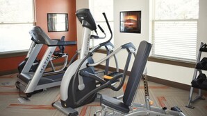 Une salle de sport équipée de tapis de course, d’un appareil elliptique et d’un banc de musculation.