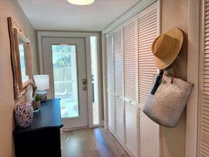 A hallway with a door leading to an outdoor area, a mirror, a vase, and a hat hanging on the wall. - Longboat Key Paradise! Pool ~ Beach ~  Kayaking ~ Shopping (Longboat Key)
