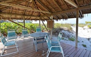 A wooden deck with a thatched roof, outdoor seating, and a view of the beach. - Longboat Key Paradise! Pool ~ Beach ~  Kayaking ~ Shopping (Longboat Key)
