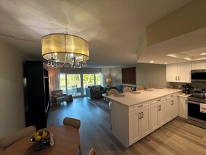 A modern kitchen with a central island, a dining area with a table and chairs, and a living room with a sofa and a coffee table. - Longboat Key Paradise! Pool ~ Beach ~  Kayaking ~ Shopping (Longboat Key)