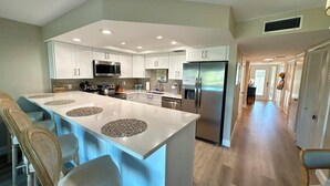 Una cocina moderna con una isla central, electrodomésticos de acero inoxidable y un pasillo largo.