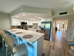 A modern kitchen with a central island, stainless steel appliances, and a long hallway. - Longboat Key Paradise! Pool ~ Beach ~  Kayaking ~ Shopping (Longboat Key)