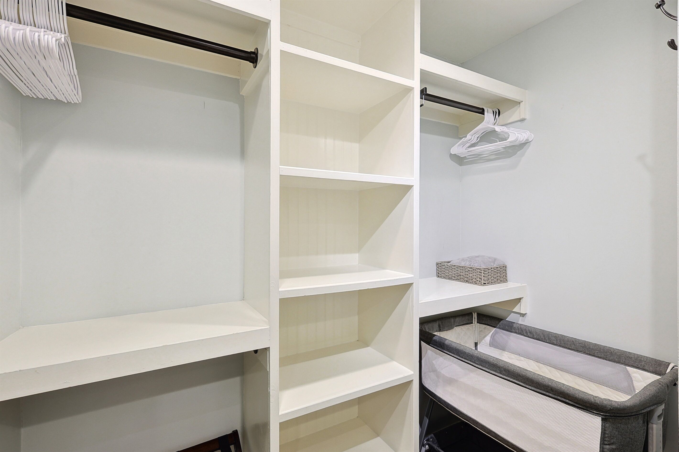 A white closet with multiple shelves and hanging space.