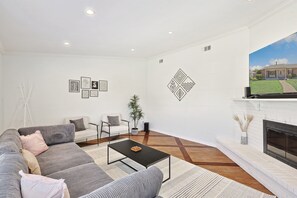 Una sala de estar moderna con un sofá modular, una mesa de centro, una chimenea y una gran pantalla de televisión.