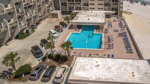 A rooftop pool with a view of the beach, surrounded by a parking area and a multi-story building with balconies. - Pinnacle Paradise 336-Gulf Views-Sleeps 7 (Panama City Beach)