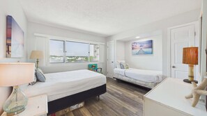 A bedroom with two beds, a window, a door, and a lamp. - Pinnacle Paradise 336-Gulf Views-Sleeps 7 (Panama City Beach)