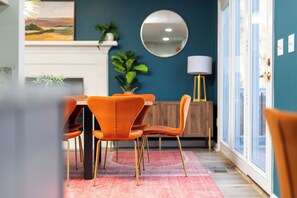 Un coin repas comprenant une table et des chaises, une cheminée, un miroir et une lampe.