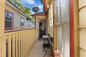 A narrow outdoor corridor with a wooden deck, a small table with chairs, and a door leading to an interior space. - Prime 2BR Upstairs Unit in the heart of Sacramento (Sacramento)