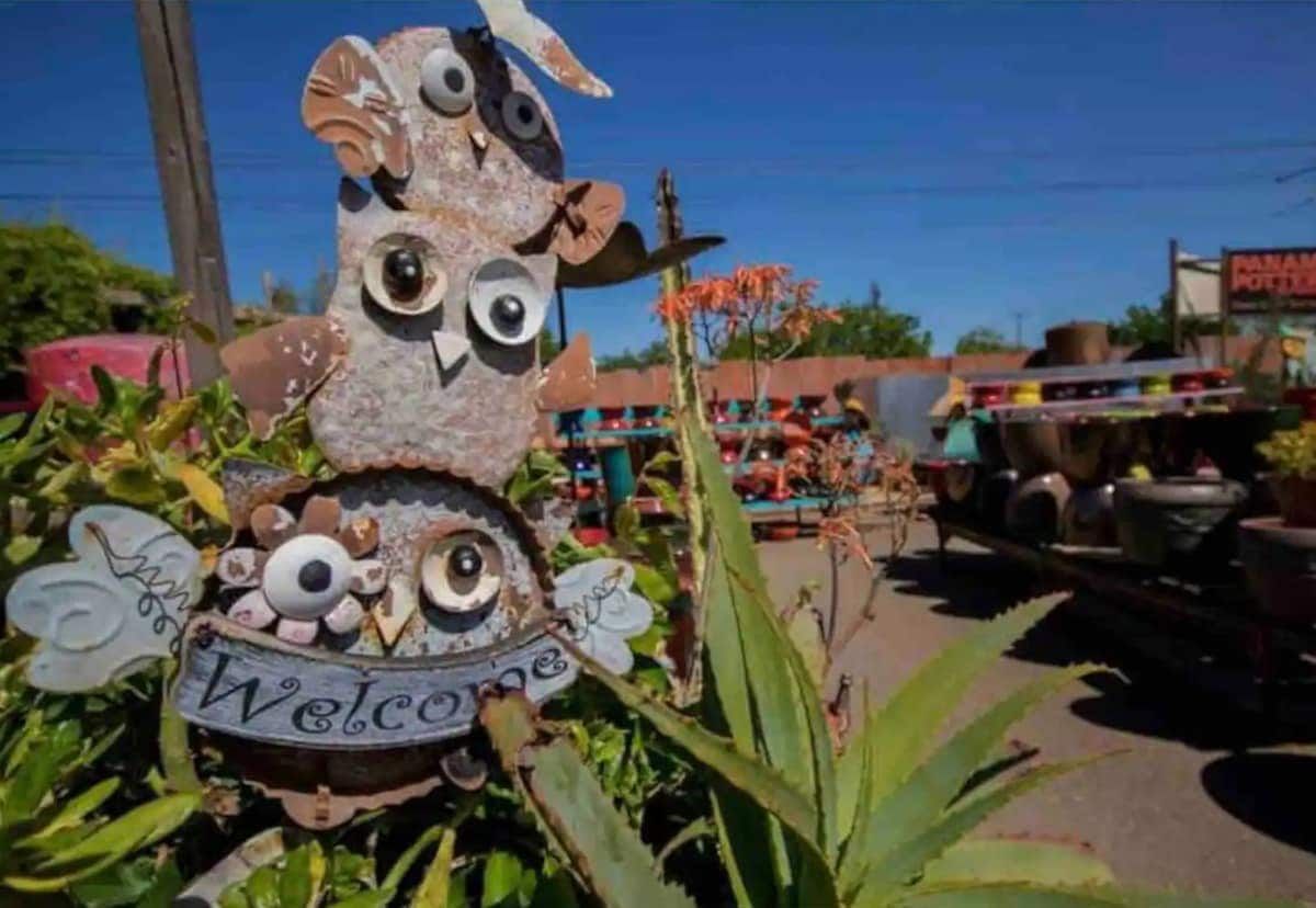 Un letrero decorativo de un búho con un cartel de 'Welcome', rodeado de follaje.
