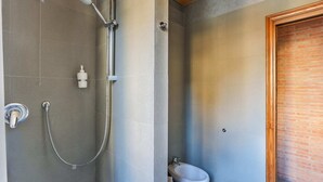 A bathroom with a shower, a toilet, and a bidet.