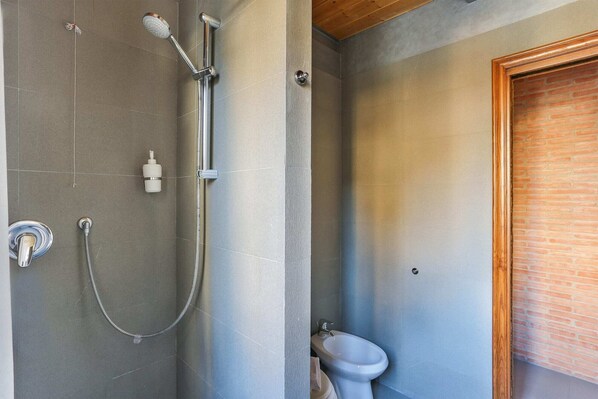 A bathroom with a shower, a toilet, and a bidet.