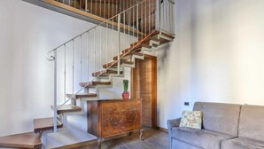 A staircase with wooden steps and metal railings, a wooden cabinet, and a sofa with a cushion.