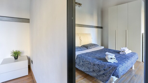 A modern bedroom with a bed, bedside table, and a wardrobe.