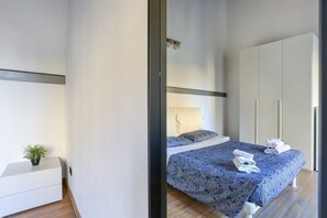 A modern bedroom with a bed, bedside table, and a wardrobe.