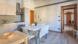 A modern kitchen with a dining area, wooden cabinets, a stove, and a dining table with chairs.