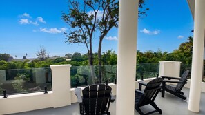 A balcony with a glass railing, two black chairs, and a table.