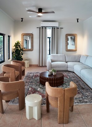 A modern living room with a sectional sofa, two armchairs, a coffee table, and a small side table.