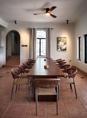 A conference room with a long table, wicker chairs, a ceiling fan, and a large window with curtains. - Luxury 7-bedroom villa with Ocean Views & Pool in Mt. Irvine (Mt. Irvine)