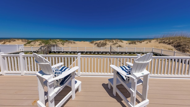 A deck with white Adirondack chairs and a view of the beach. - Seas the Moment - 4 BR Oceanfront with Pool (Virginia Beach)