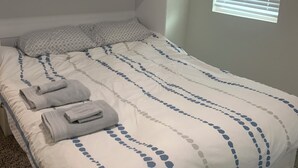 A neatly made bed with a patterned bedspread, a framed picture on the wall, and a window with blinds. - Awesome 3-bedroom house 1.5 miles to Lake Texoma & 5 miles to Megastar casino (Gordonville)