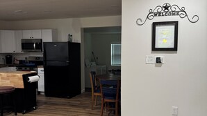 A kitchen with white cabinets, a black refrigerator, and a wooden dining table with chairs. - Awesome 3-bedroom house 1.5 miles to Lake Texoma & 5 miles to Megastar casino (Gordonville)