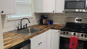 A modern kitchen with white cabinets, a stainless steel dishwasher, a microwave, and a stove. - Awesome 3-bedroom house 1.5 miles to Lake Texoma & 5 miles to Megastar casino (Gordonville)