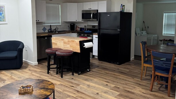 A modern kitchen with white cabinets, a black refrigerator, and a microwave. There is a dining area with a wooden table and chairs, and a ceiling fan. - Awesome 3-bedroom house 1.5 miles to Lake Texoma & 5 miles to Megastar casino (Gordonville)