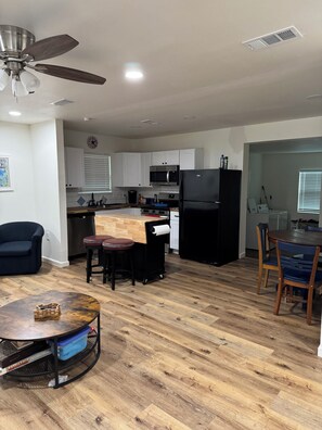 A modern kitchen with white cabinets, a black refrigerator, and a microwave. There is a dining area with a wooden table and chairs, and a ceiling fan. - Awesome 3-bedroom house 1.5 miles to Lake Texoma & 5 miles to Megastar casino (Gordonville)
