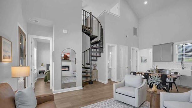 Amplia sala de estar con una escalera espiral, chimenea y comedor con muebles modernos.