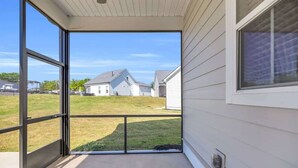 Un espacio al aire libre techado con vistas a casas cercanas y un jardín con césped.