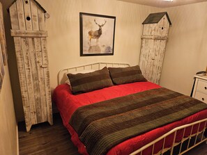 A bedroom with a bed, a framed deer picture, and rustic wooden decor. - Peaceful 2 bedroom cabin 4 Miles from Red Lodge perfect for relaxing getaways. (Roberts)