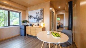A modern kitchen with a dining area, a large window, and a painting on the wall. - Church Bay Views & Guesthouse (Waiheke Island)