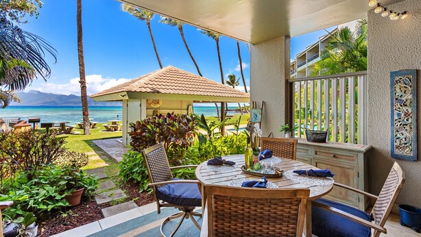 A covered outdoor dining area with a view of the ocean, a small gazebo, and a dining table set with chairs. - Oceanfront 1BR Condo Steps to Beach West Maui (Honokowai)
