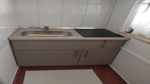 Cocina compacta con lavamanos, armarios y encimera.