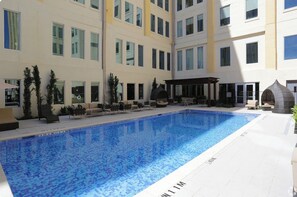 A swimming pool with a tiled floor, surrounded by lounge chairs and a covered seating area. - Luxurious Downtown Dallas Loft +
Skyline Views +Resort Amenities (Dallas)