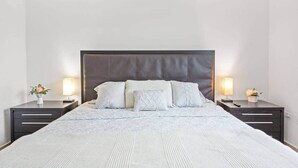 Ein Bett mit dunklem Kopfteil, zwei Nachttische mit Lampen und eine Blumenkomposition auf jedem Tisch.