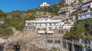 Ein Küstengebäude mit mehreren Balkonen, einer Steinfassade und Blick auf das Meer.