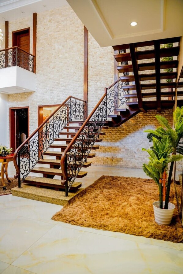 A grand staircase with ornate metal railings, a stone wall, and a potted plant. - Spacious 5BR, 2 kanal Luxury Family Home (Lahore)