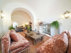 A spacious living area with a high arched doorway, a wooden coffee table, and two sofas with a distressed finish. - Villa Riggiola, Historic Villa with Sea Views (Sorrento)
