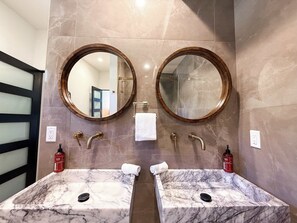 Ein Badezimmer mit zwei Marmorwaschtischen, zwei runden Spiegeln und einem Handtuchhalter.